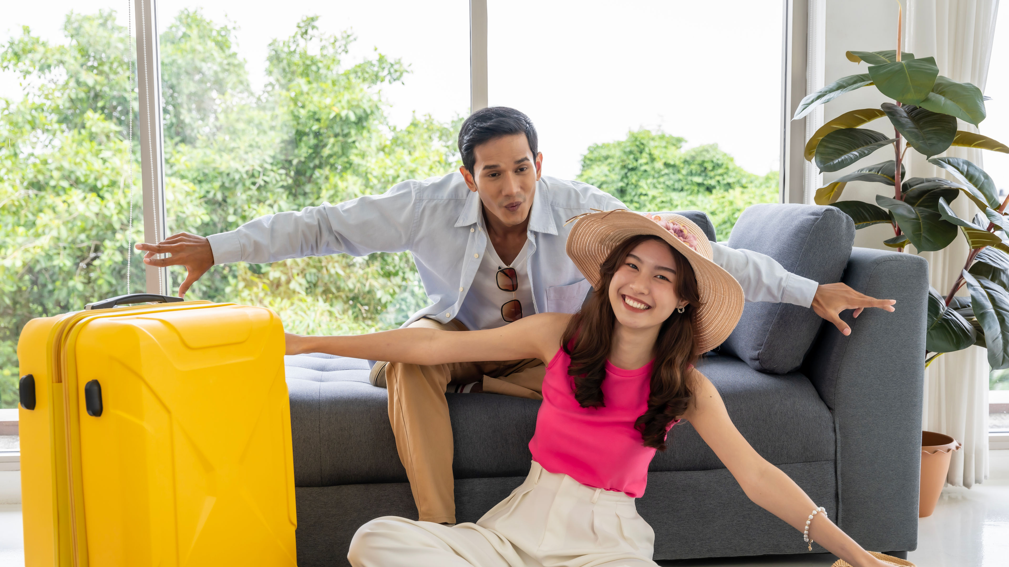 A happy Asian couple posing with a yellow trolley bag.