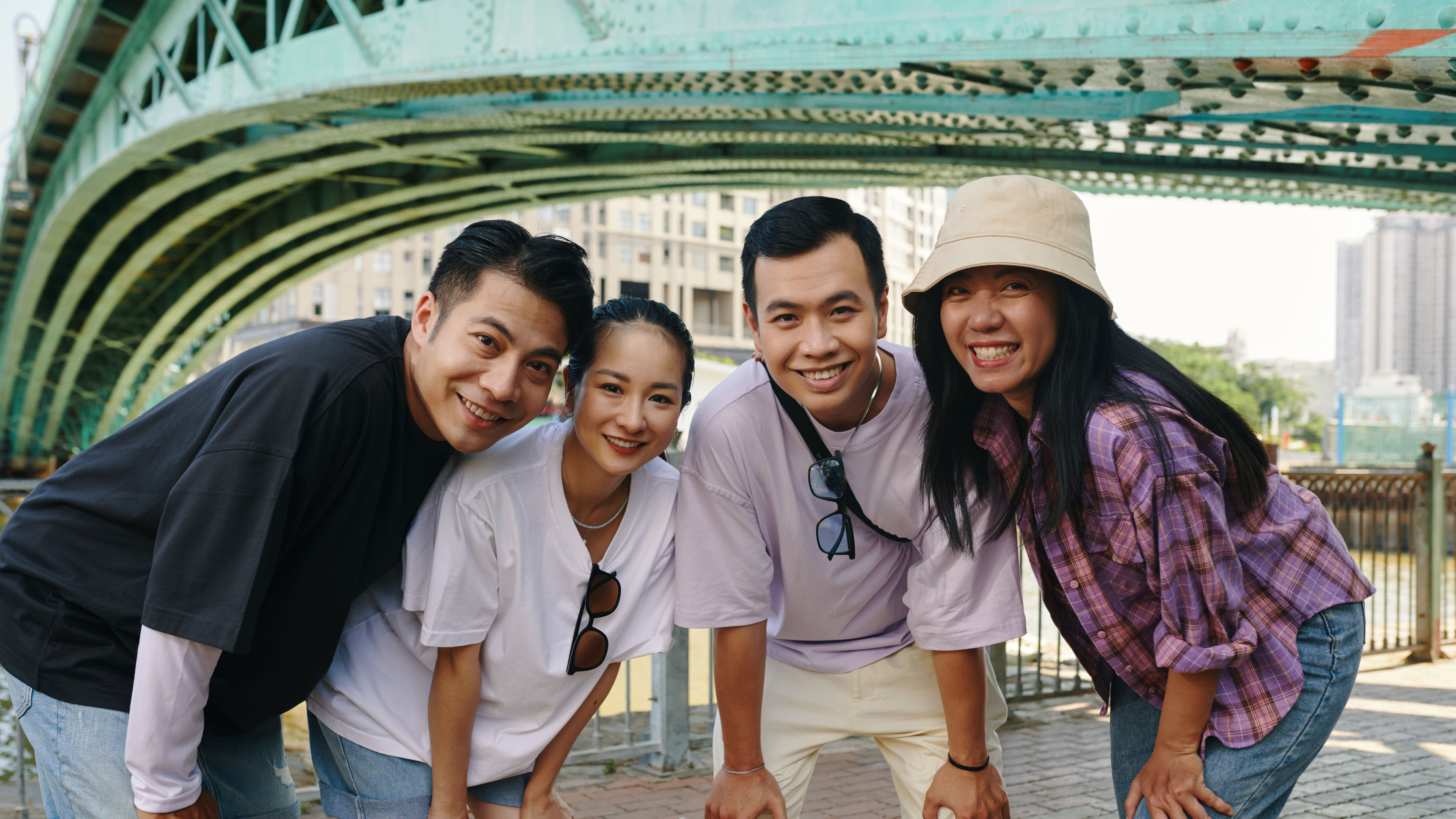 A group of friends posing under a bridge and smiling.