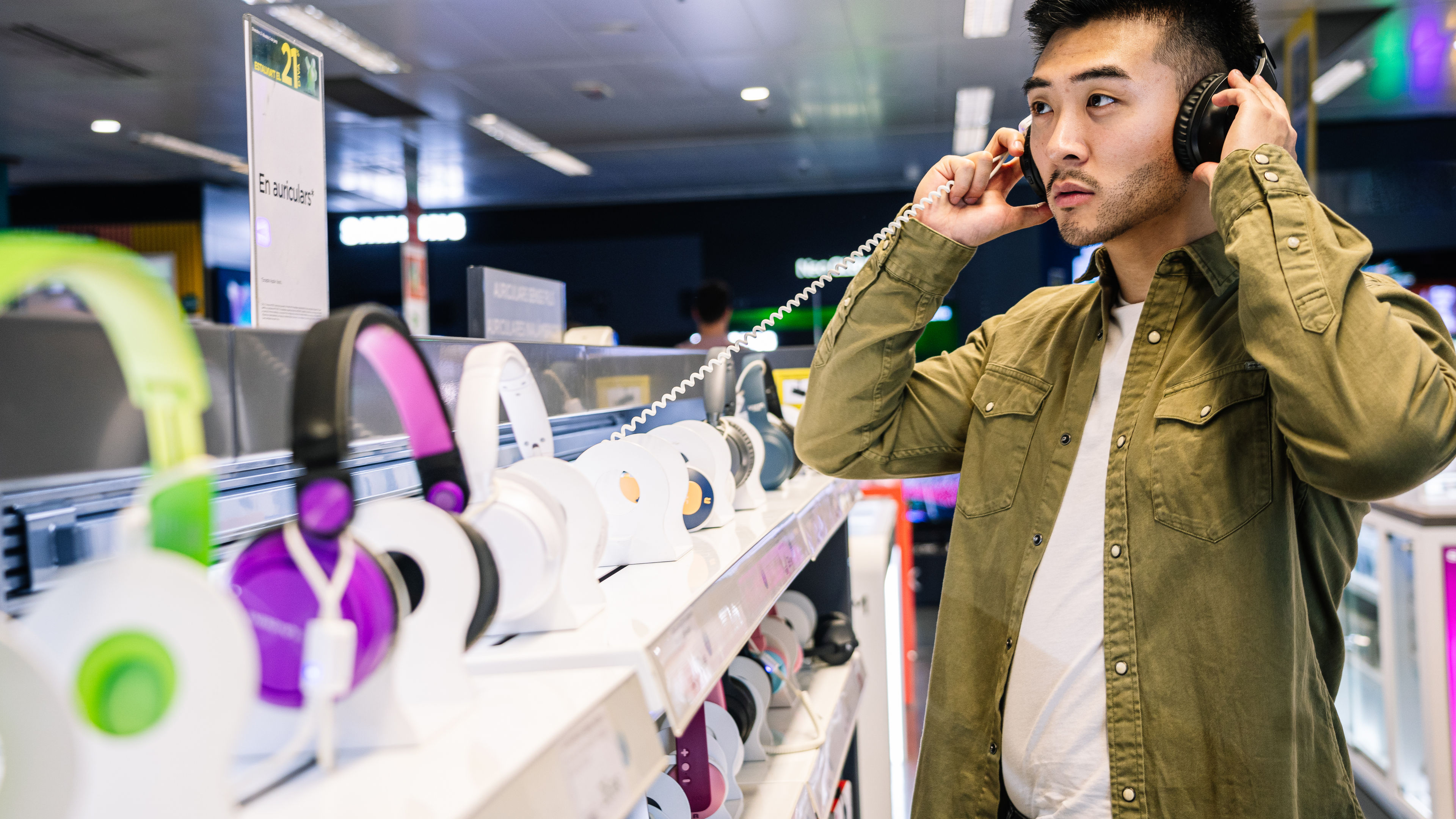 Shopper experiencing audio quality of headphones in an electronics store.