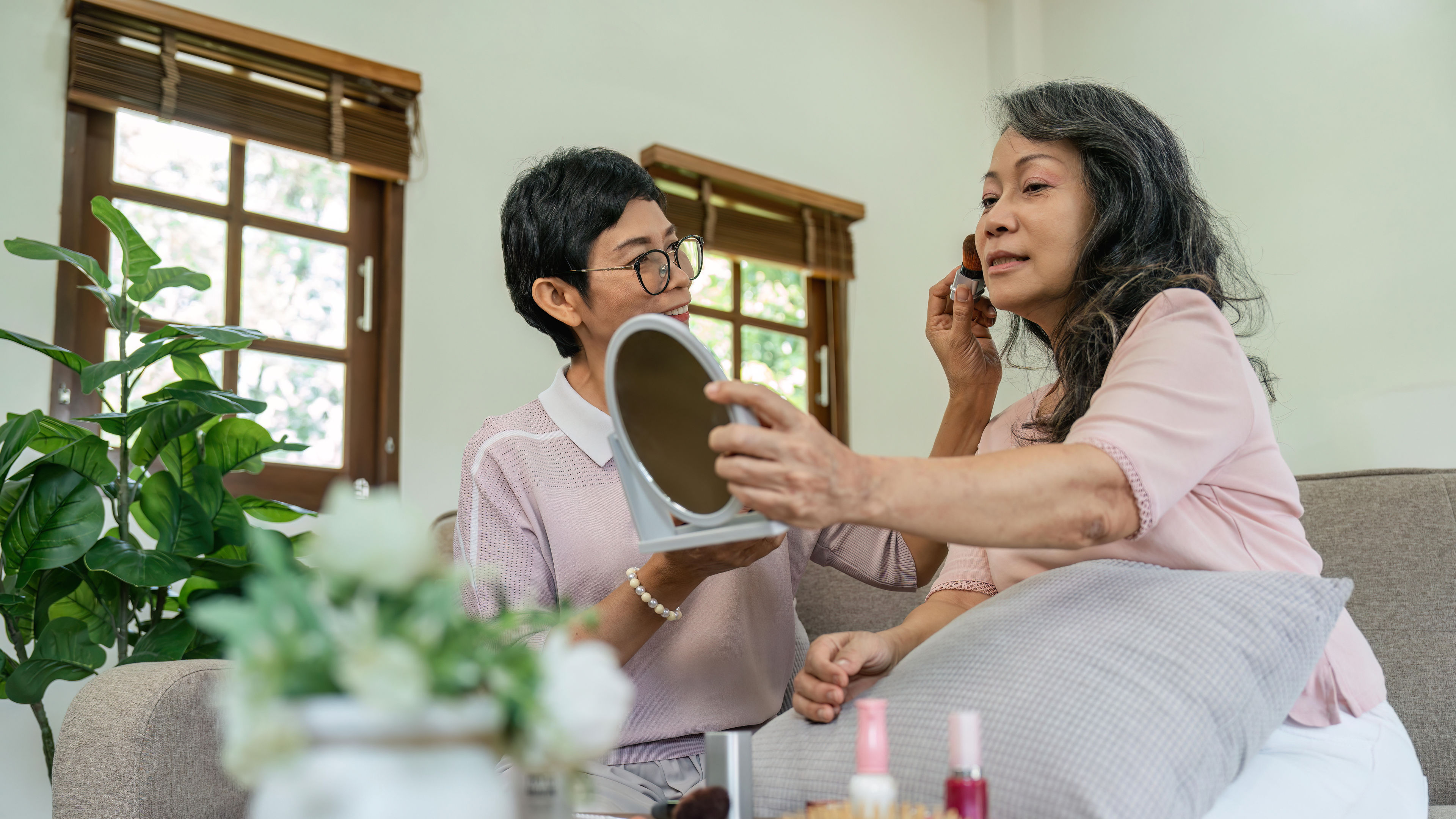 Two old women doing makeup at home.