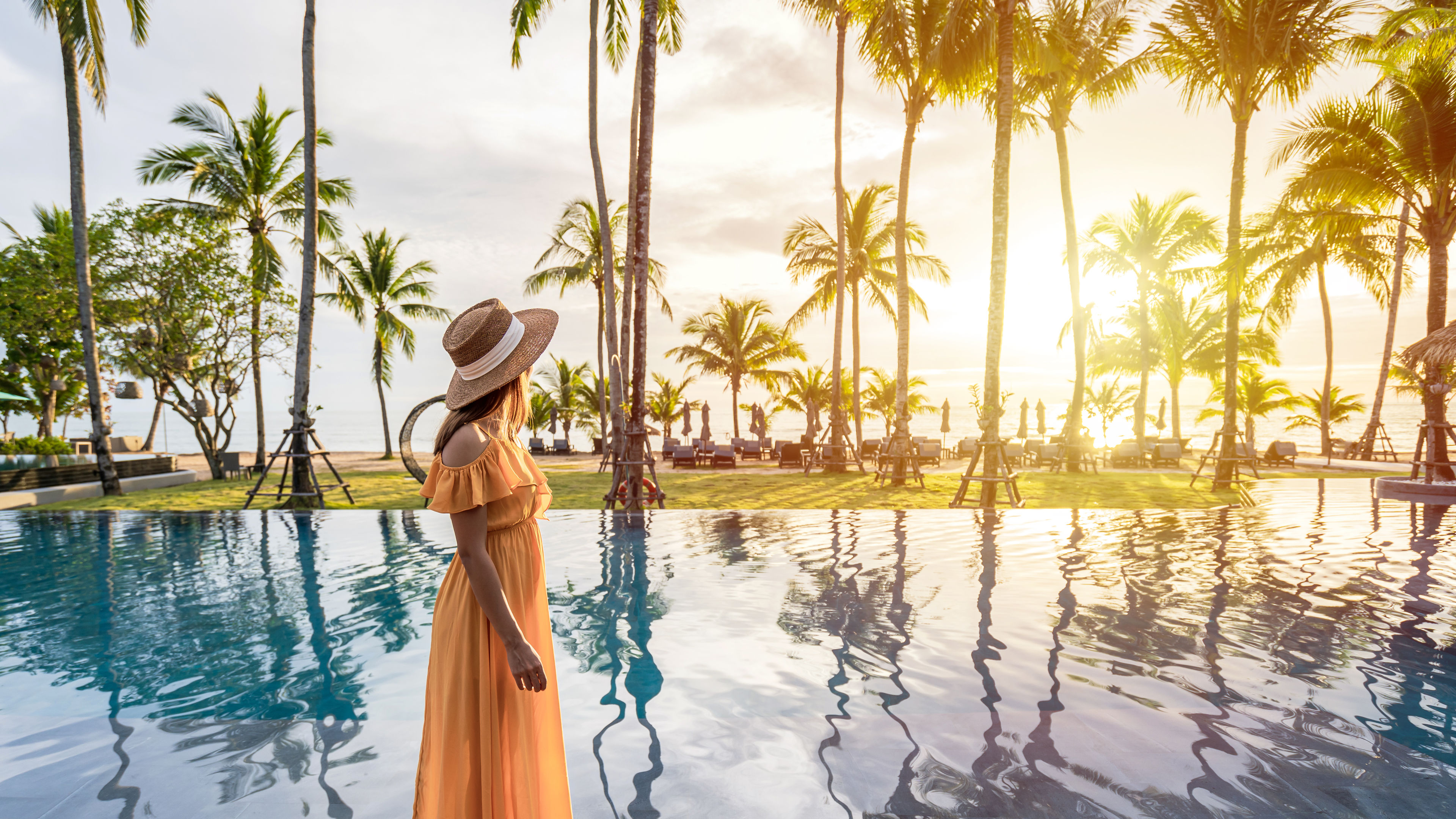 A young woman traveler enjoying the sunset by the poolside at a hotel.