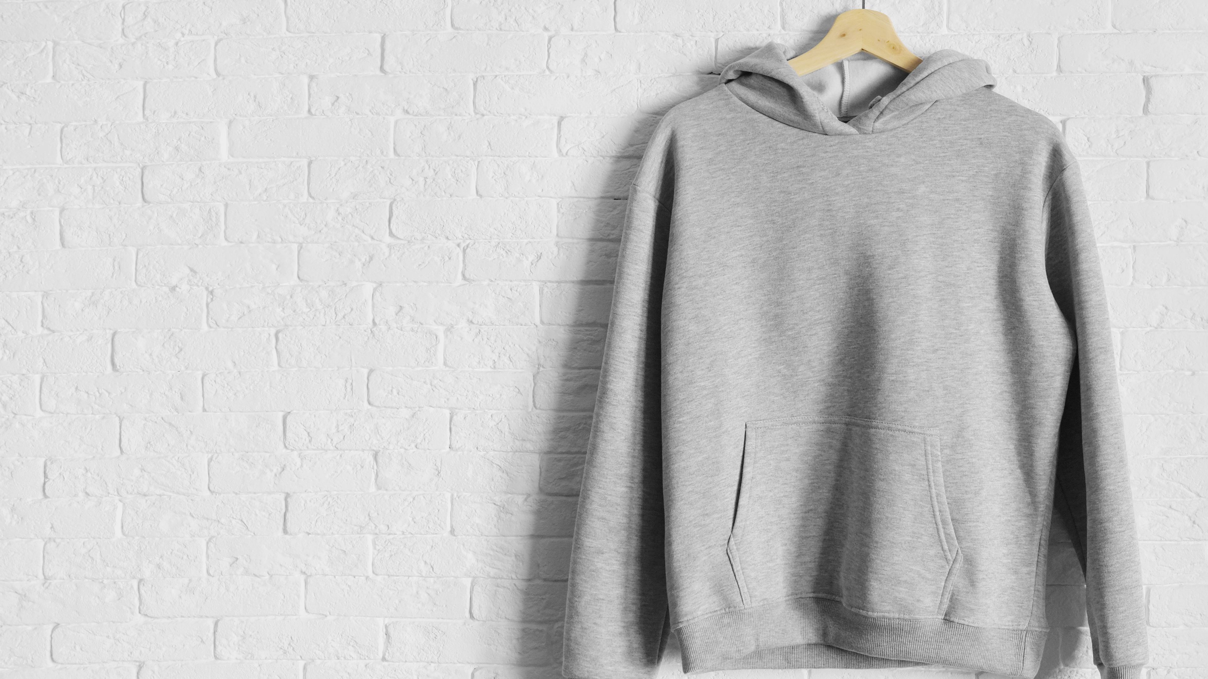 A grey hoodie hanging on a wooden hanger