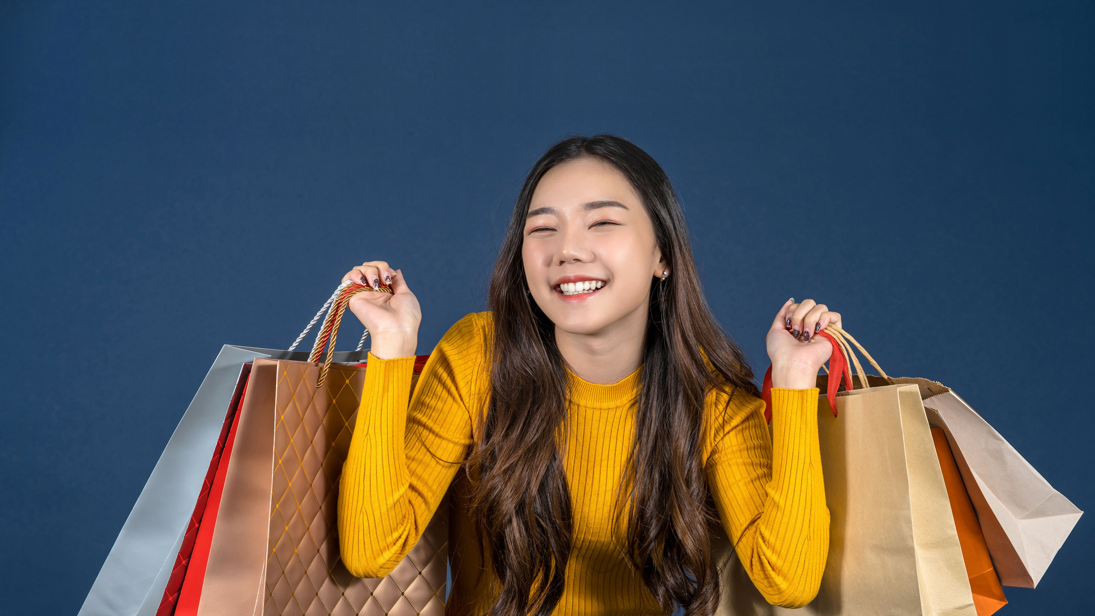 A happy woman holds multiple colourful shopping bags