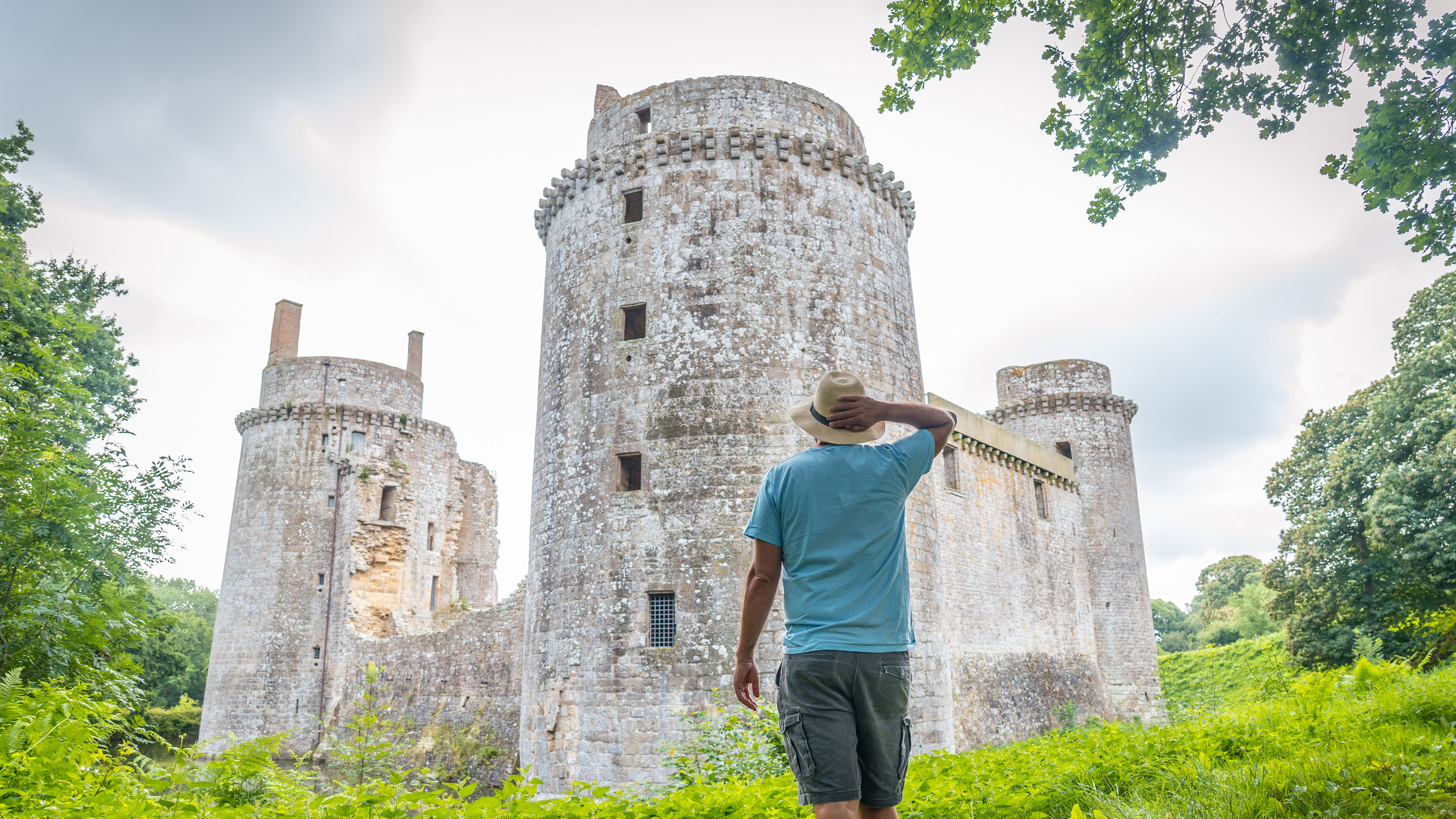 A man standing in front of a large, round stone tower.