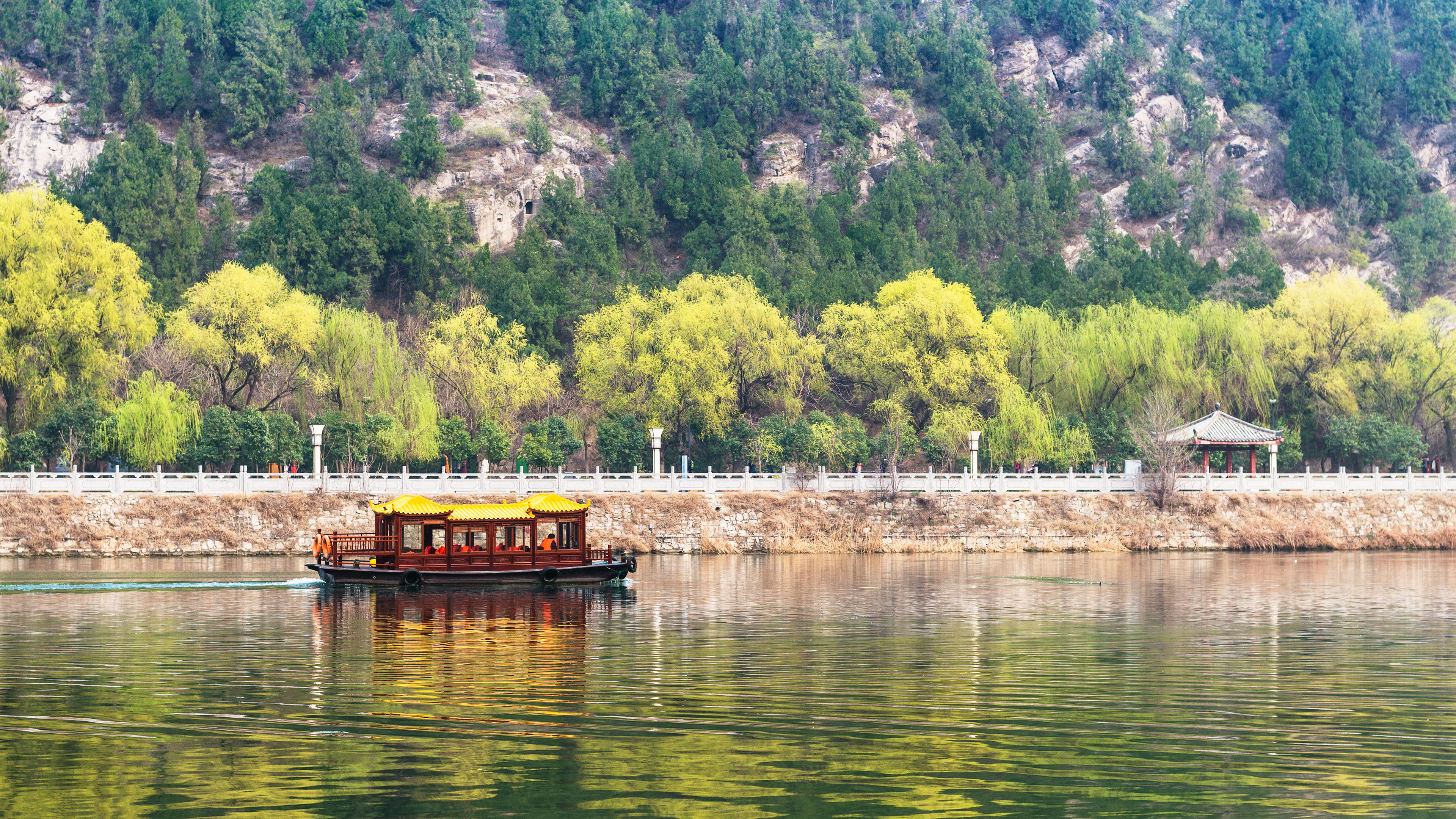 A serene wooden junk boat glides across still waters