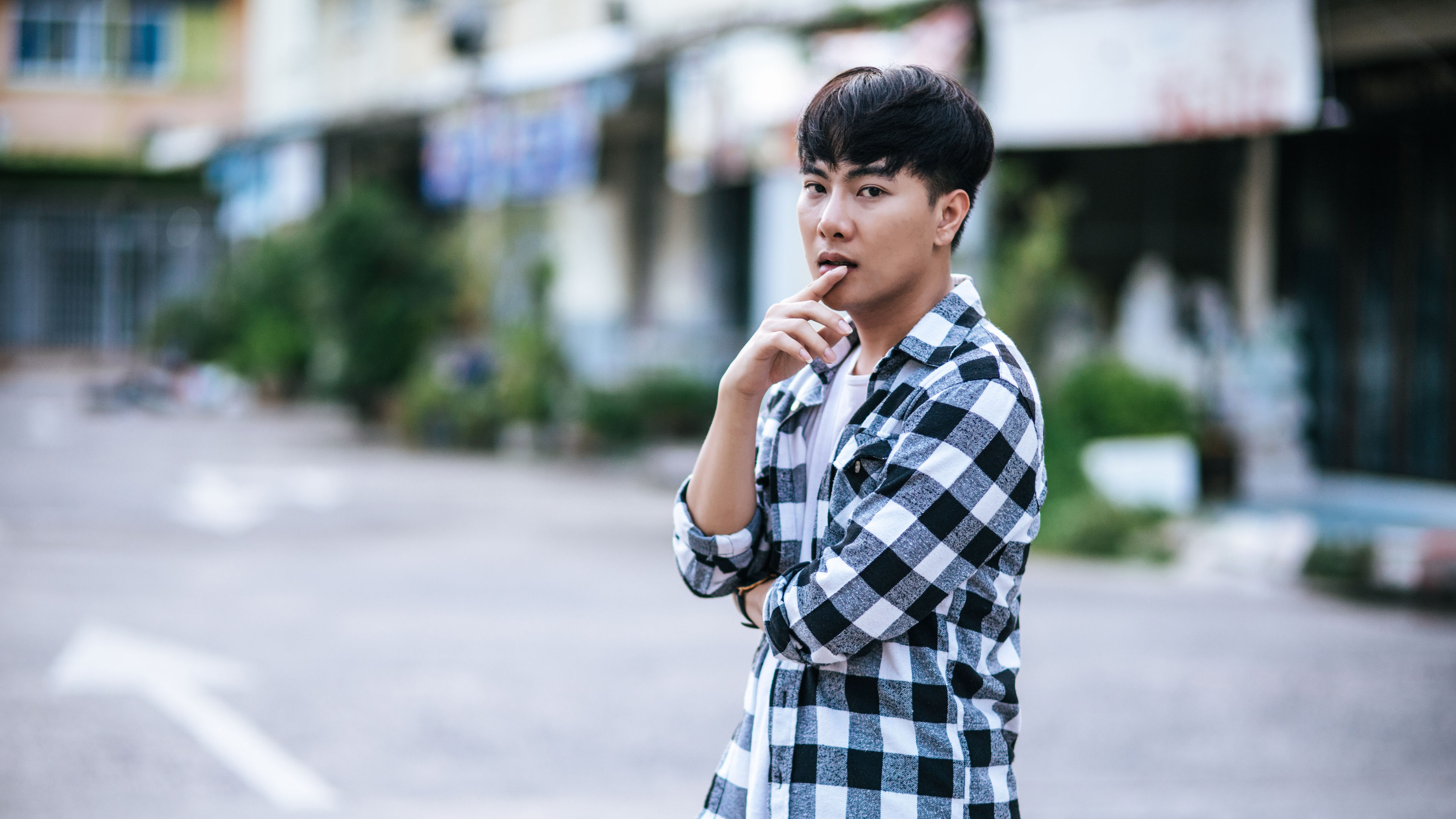 A young man in a striped shirt is standing on the street