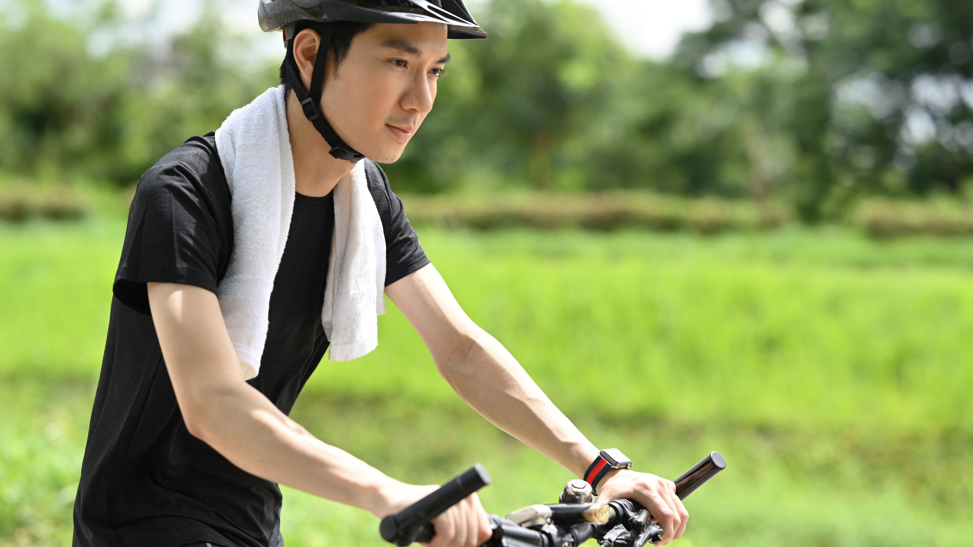 A young man is cycling wearing a helmet