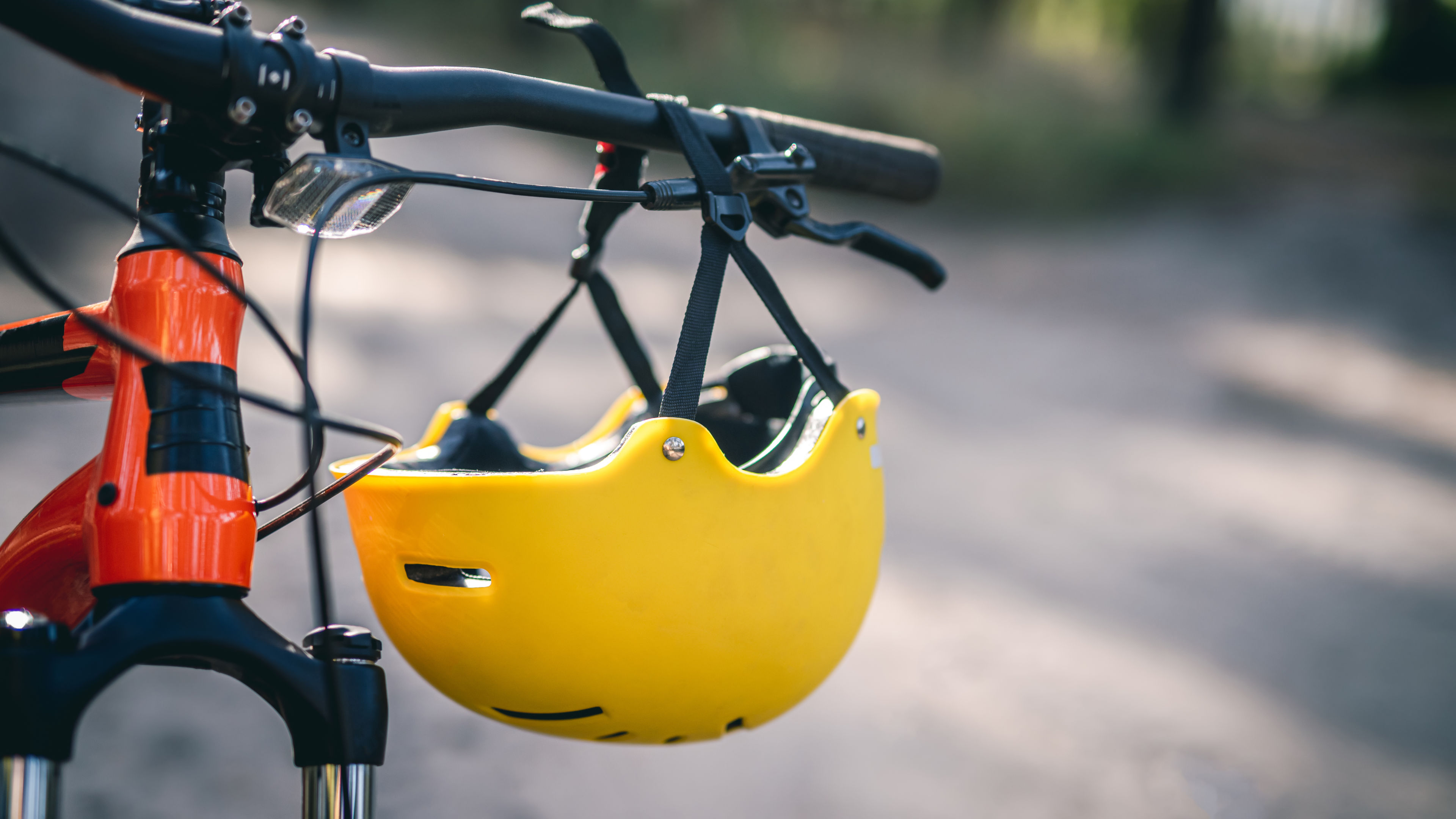 Helm kuning cerah tergantung di setang di sepeda