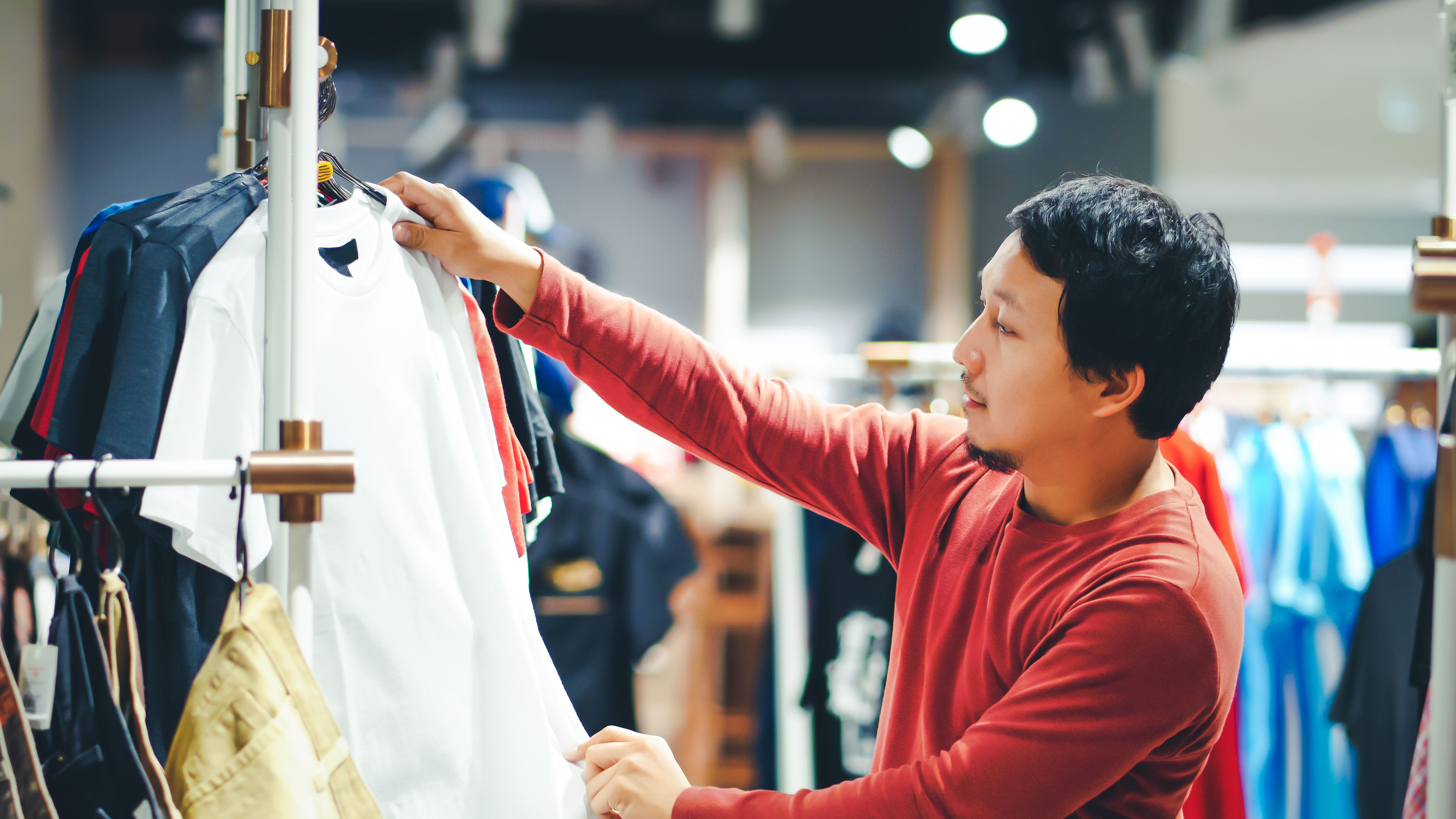 Smart man hoosing clothes in clothing store at shopping center