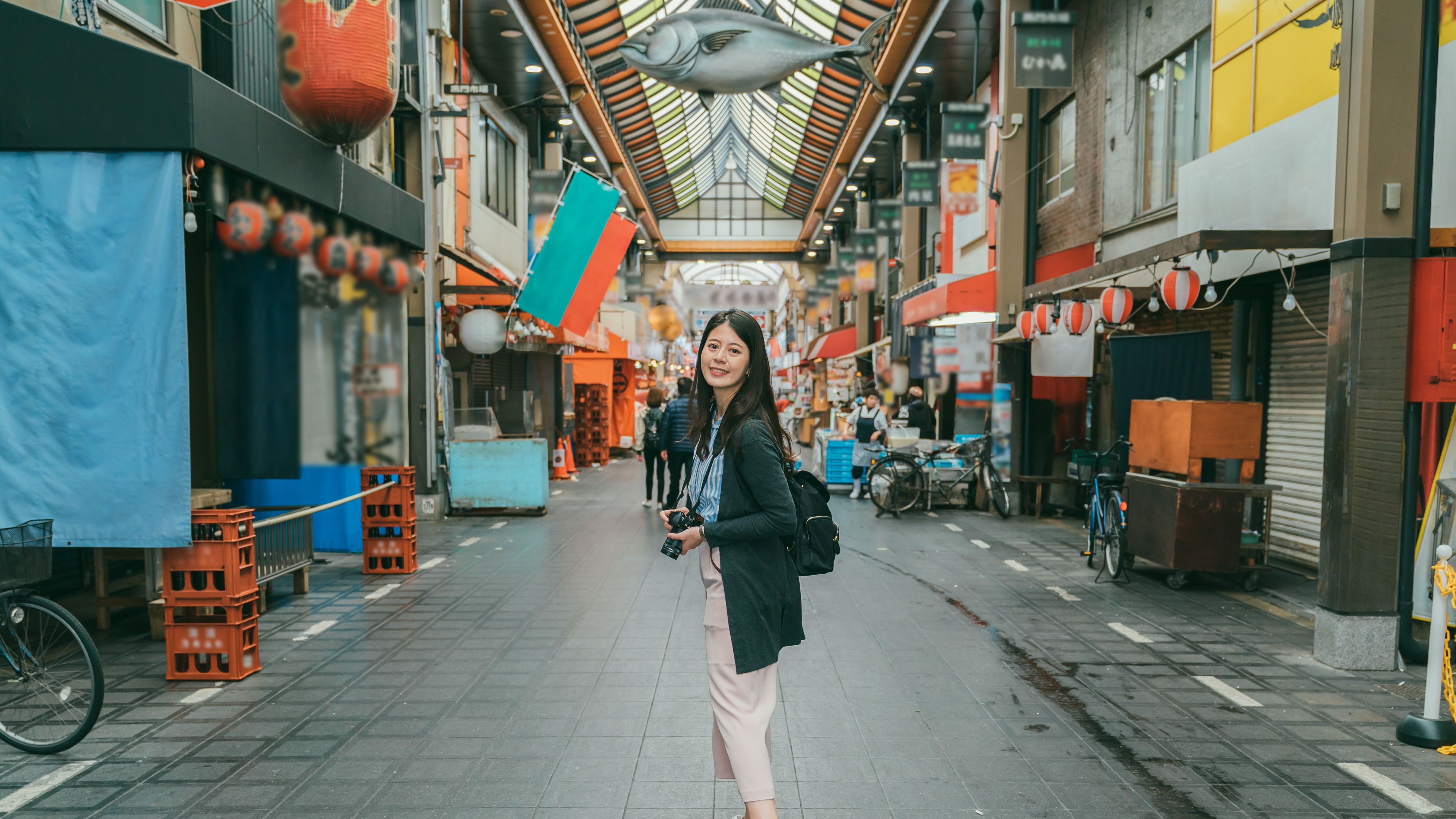 The woman holding a camera while standing in the market