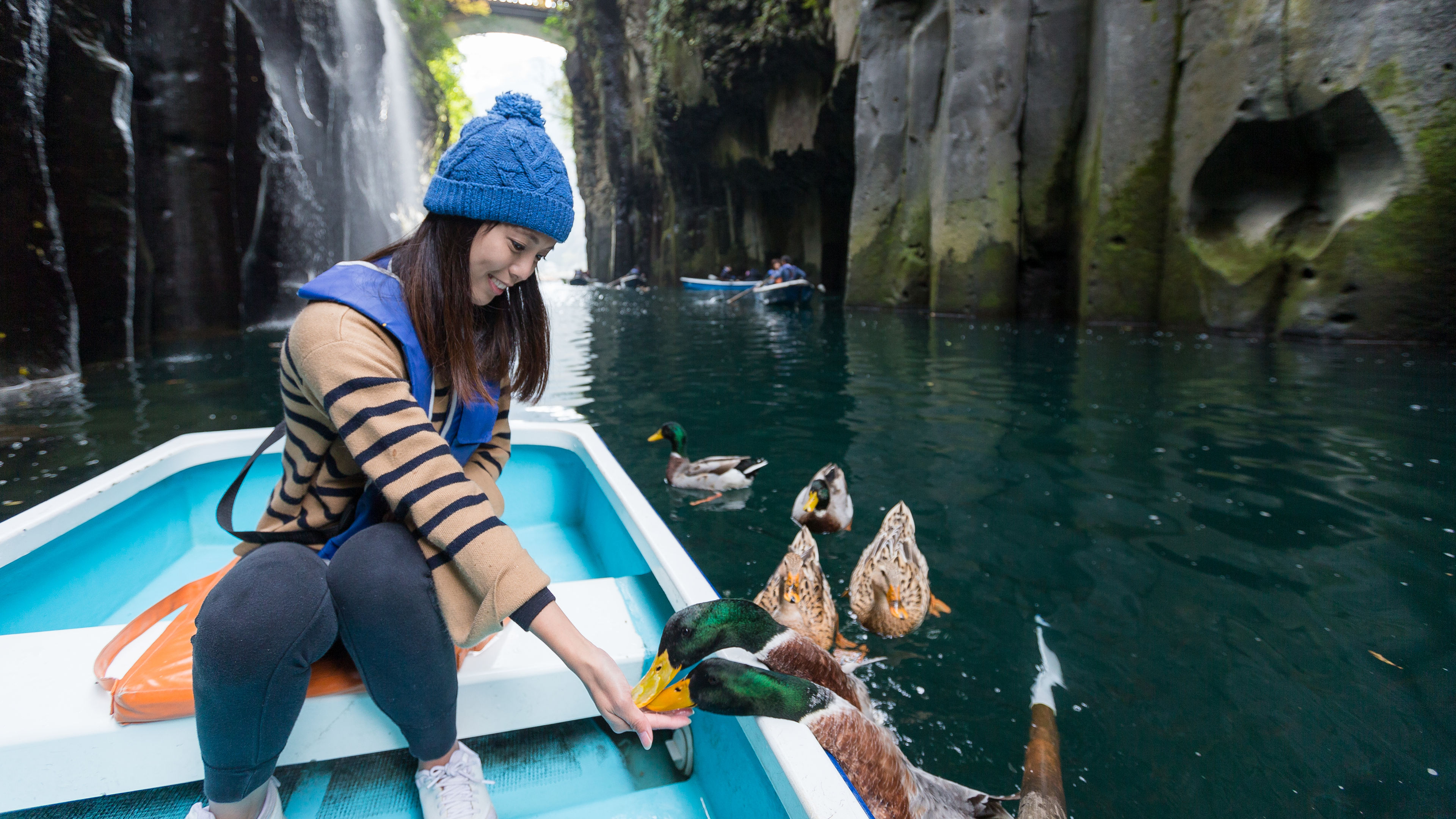 Woman feeding duck and sitting on boat