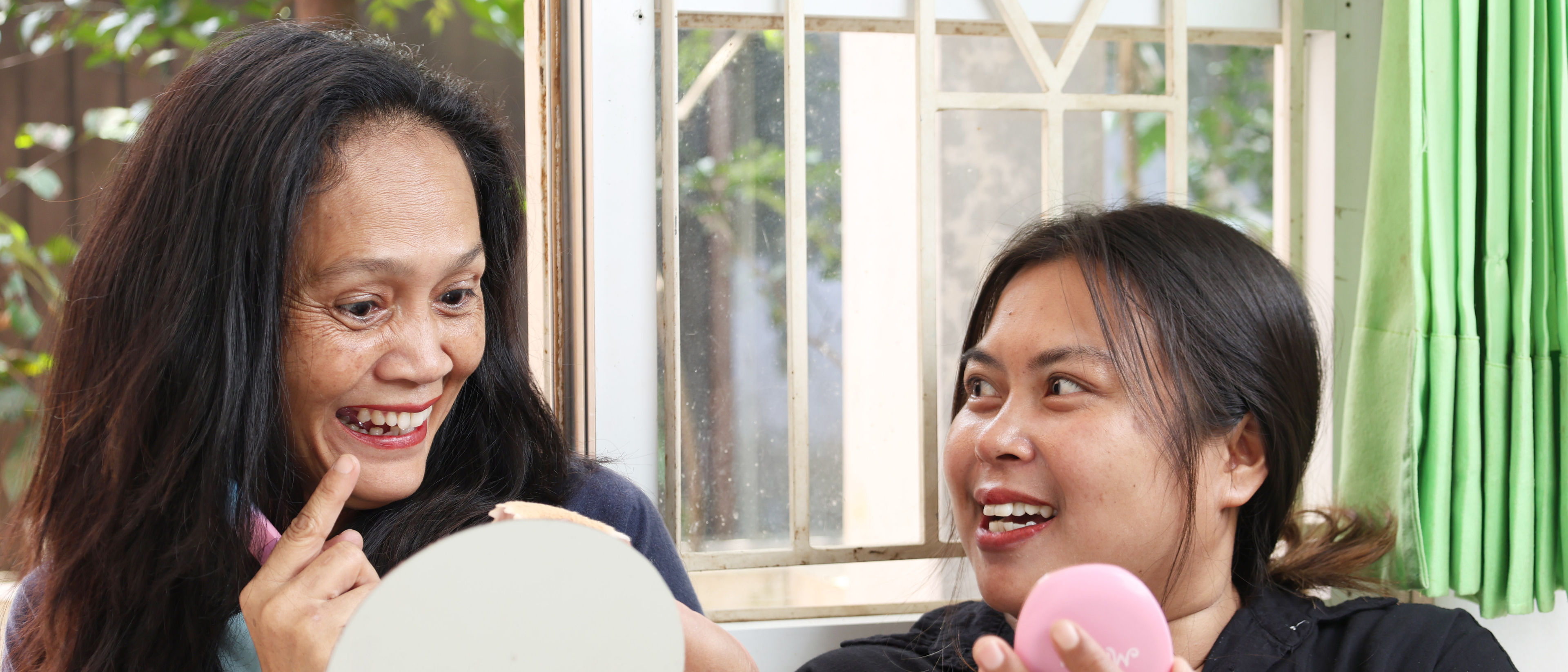 Two women chatting about makeup with products in hand.