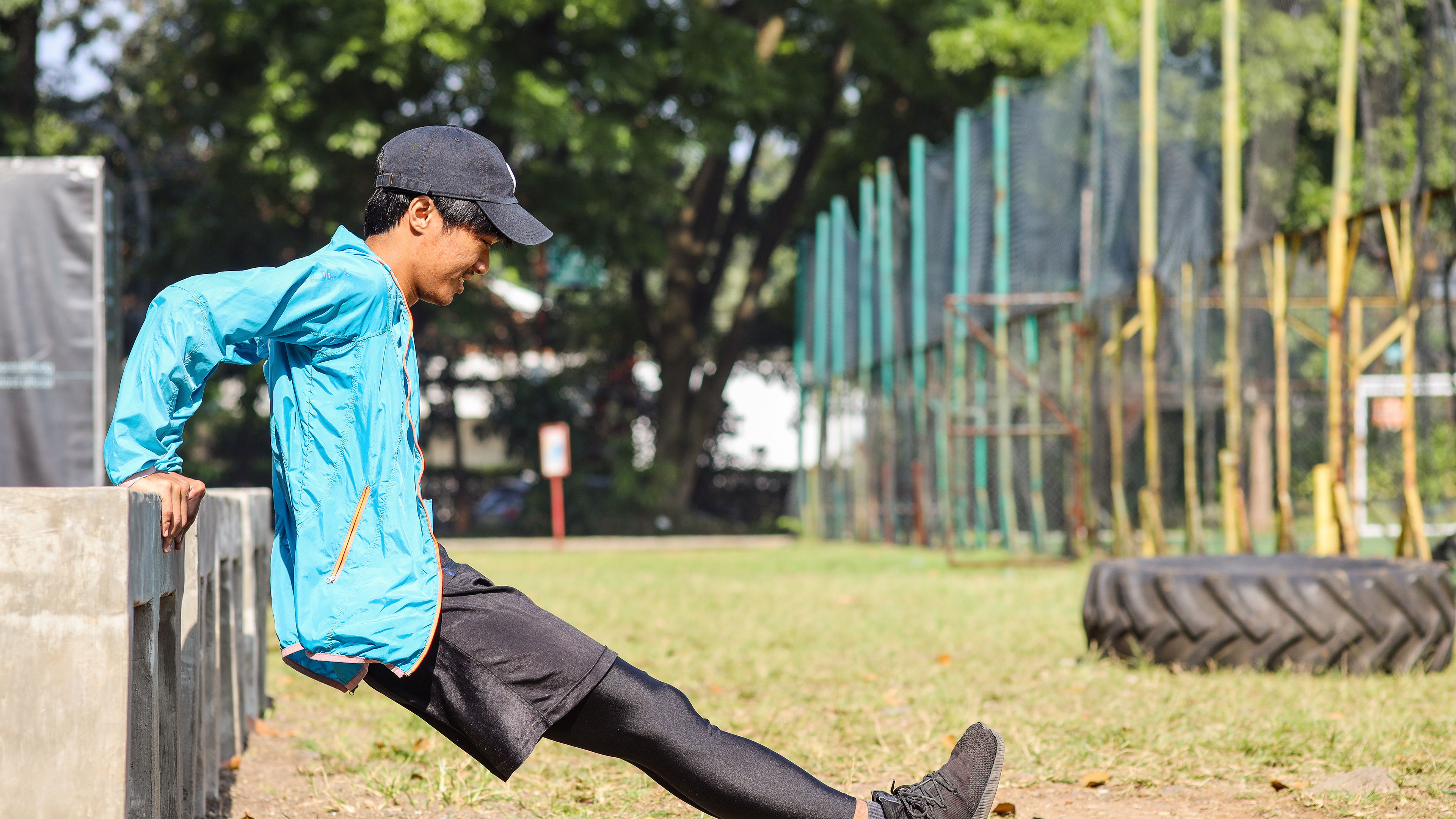 Young man in a blue jacket and black cap doing triceps 